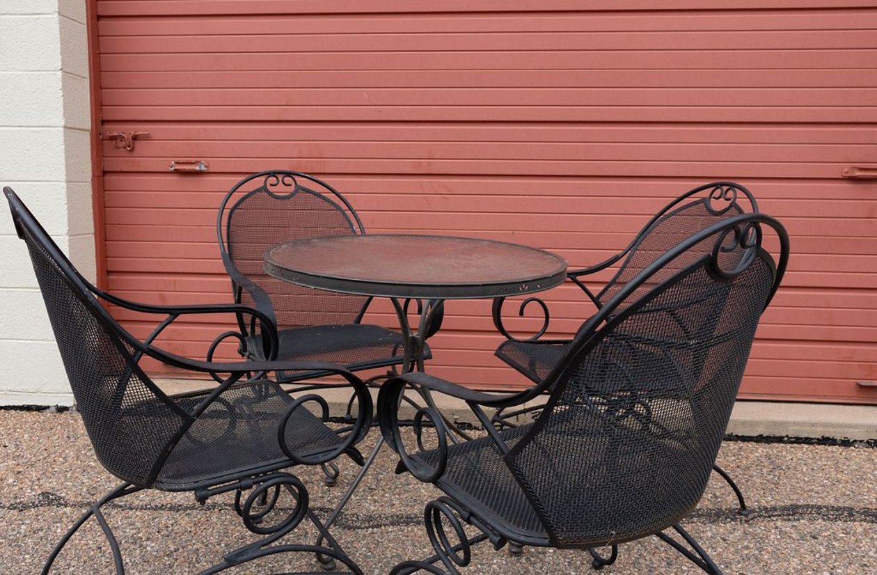 Black wrought iron outdoor patio set with round table and 4 scroll chairs