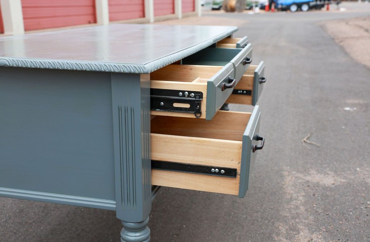 Slate blue painted vintage farmhouse desk with multiple drawers and carved fluted column details
